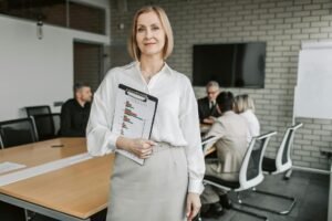 woman wearing a white blouse carrying a clipboard