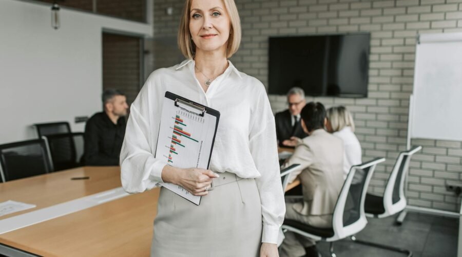 woman wearing a white blouse carrying a clipboard